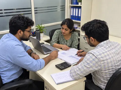 Illustrative work scene of three professionals discussing documents around a desk